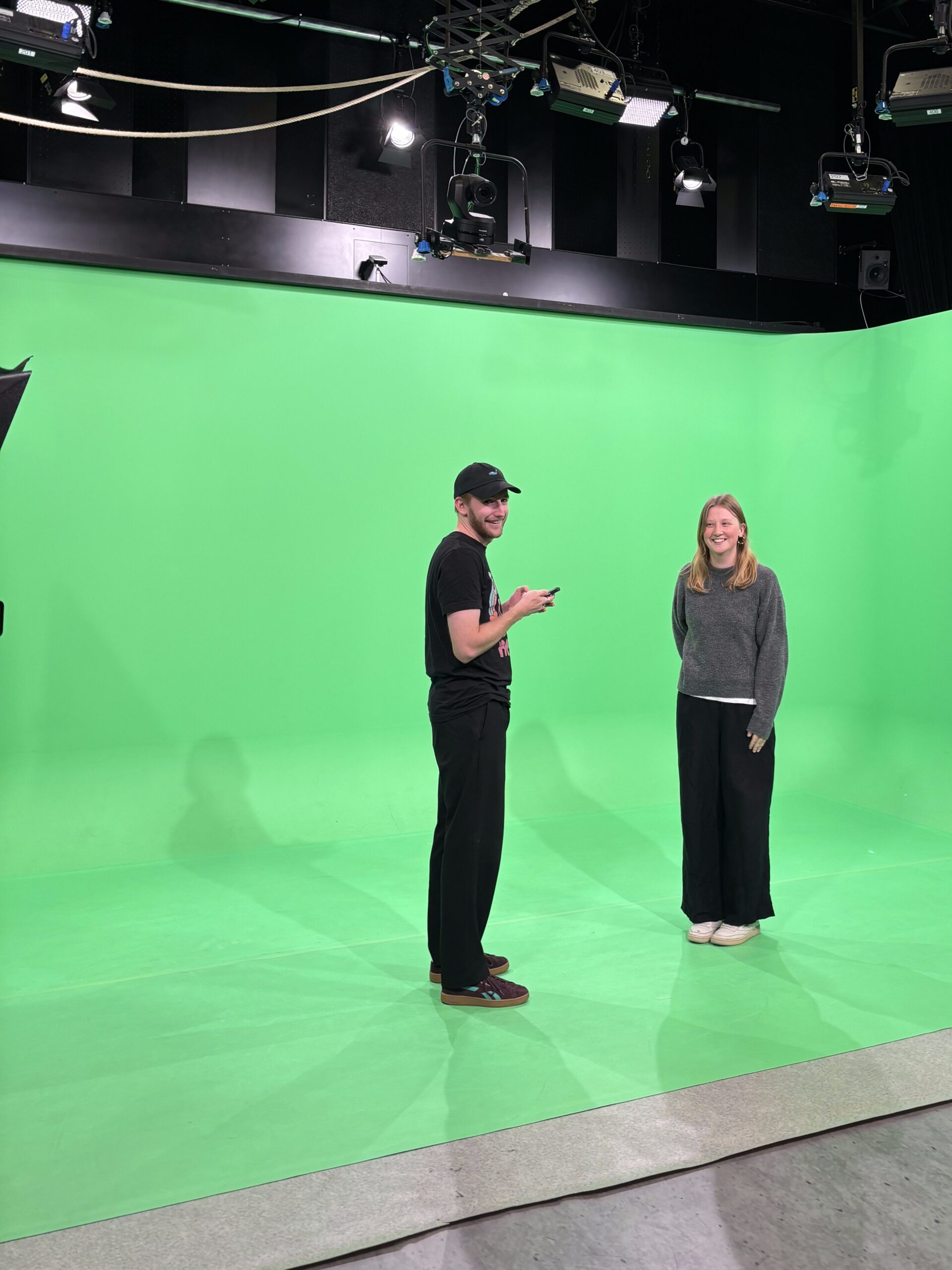 Moritz steht im Greenscreenstudio des RTR. Neben ihm steht eine Mitstudierende.