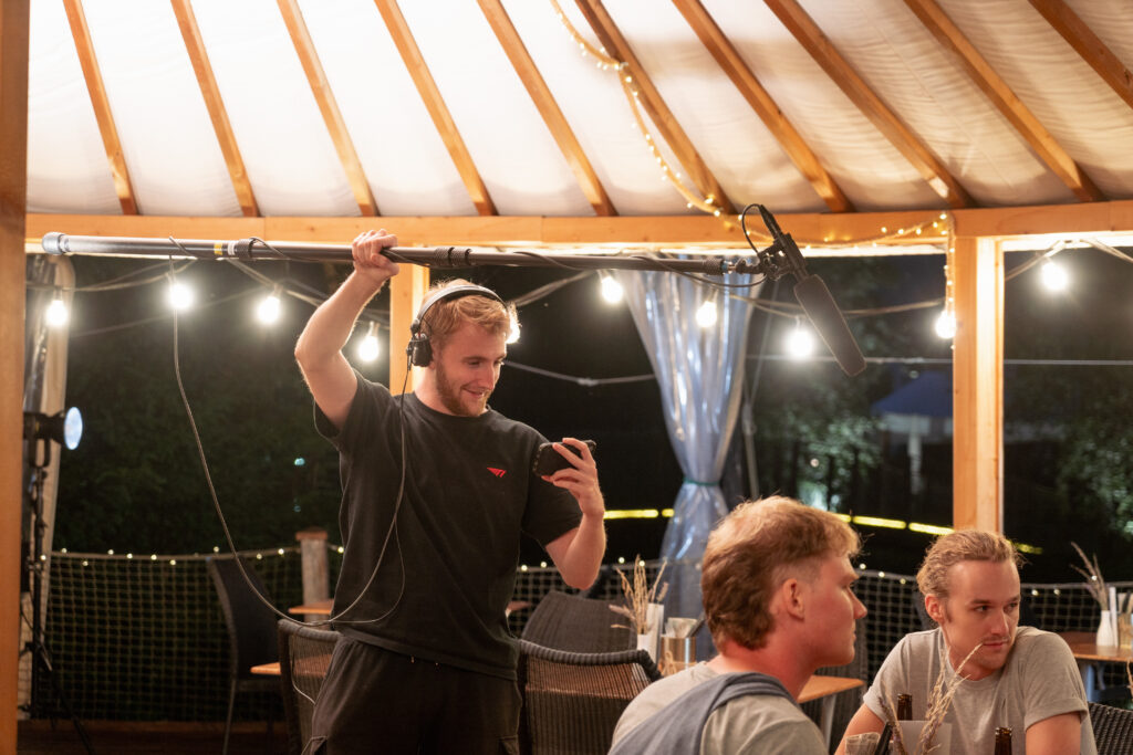Moritz Kappeler hat eine Tonangel in der Hand und schaut auf sein Smartphone.